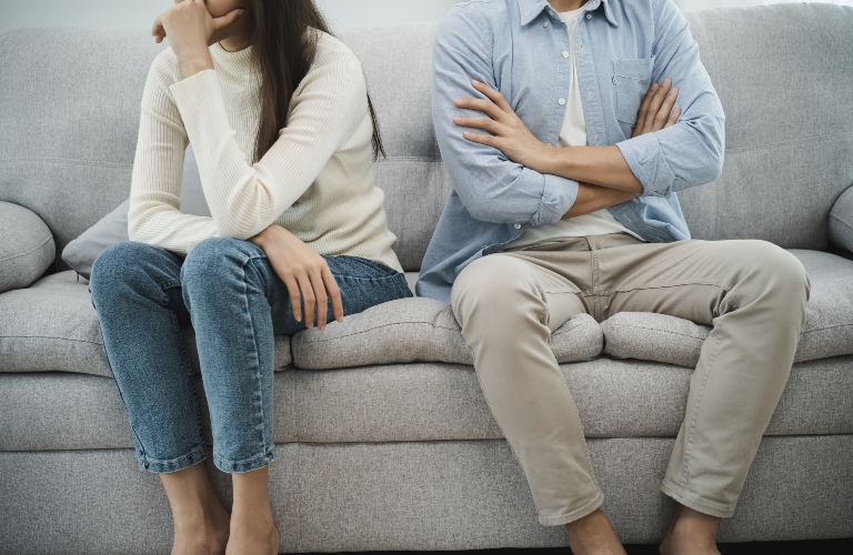 women cover her face and sit separately from husband